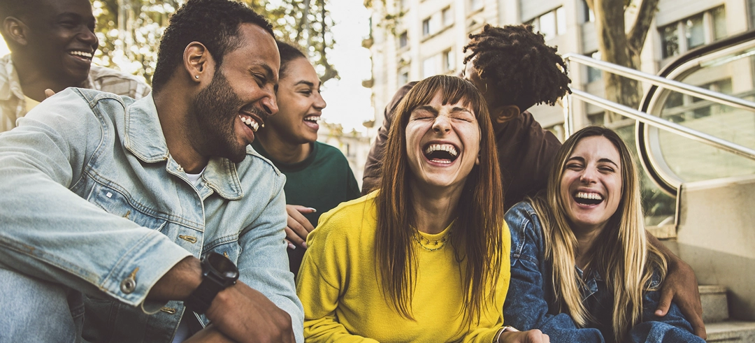 Grupo de gente sentada en una escaleras riéndose