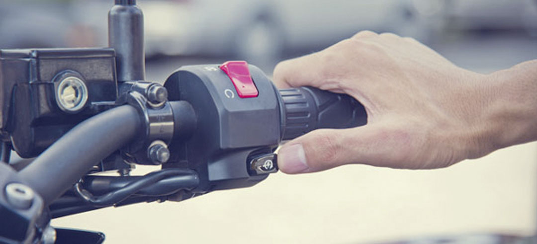 Persona arrancando una moto pulsando el botón de encendido